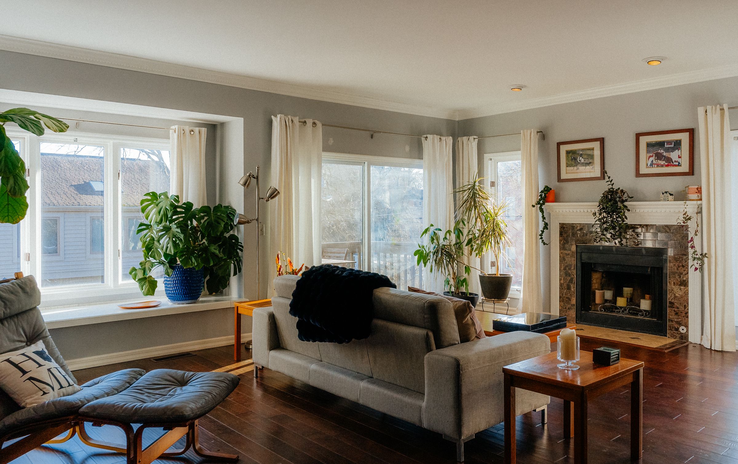 Helles Wohnzimmer mit Pflanzen, Holzfußboden, Sofa und Kamin.